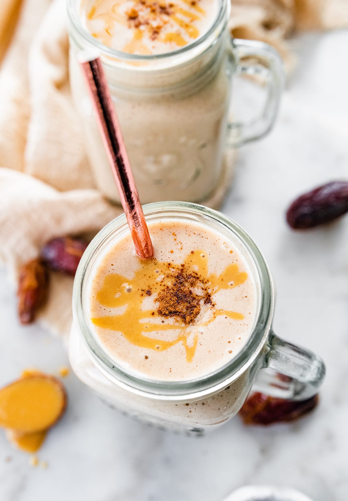 Tahini smoothie with straw, topped with tahini and cinnamon.
