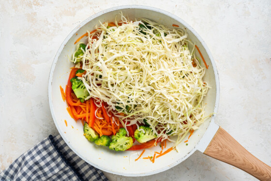 Cabbage, carrots, broccoli and red bell pepper in a skillet.