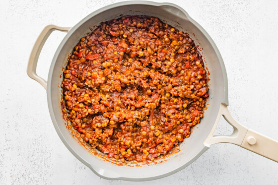 Lentils simmering in a tomato sauce in a skillet for vegan Sloppy Joes.