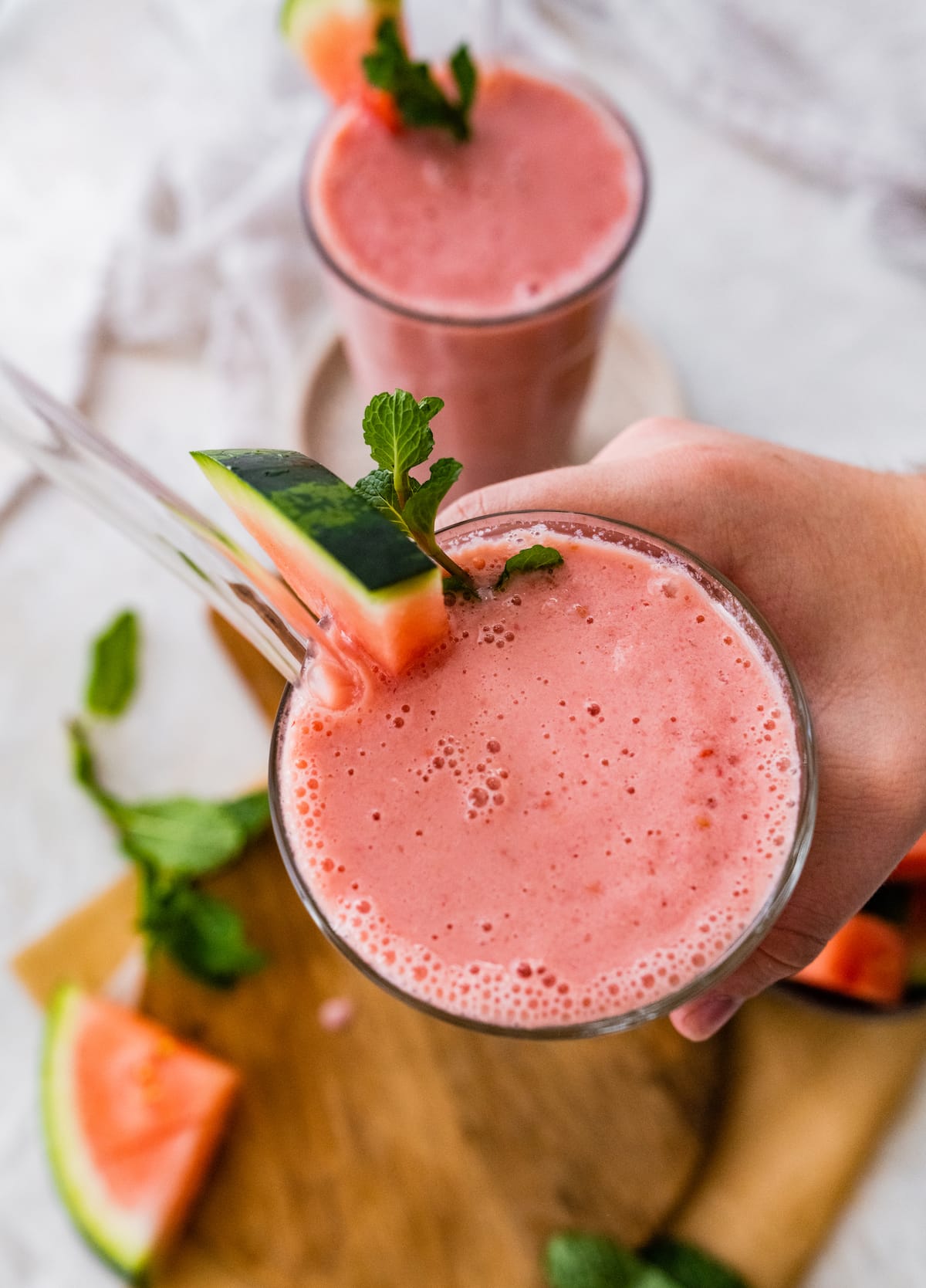 Woman's hand holding watermelon smoothie.
