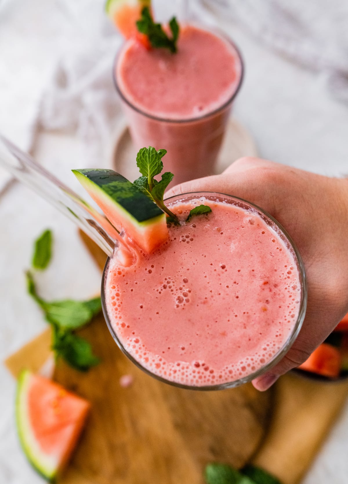 Woman's hand holding watermelon smoothie.