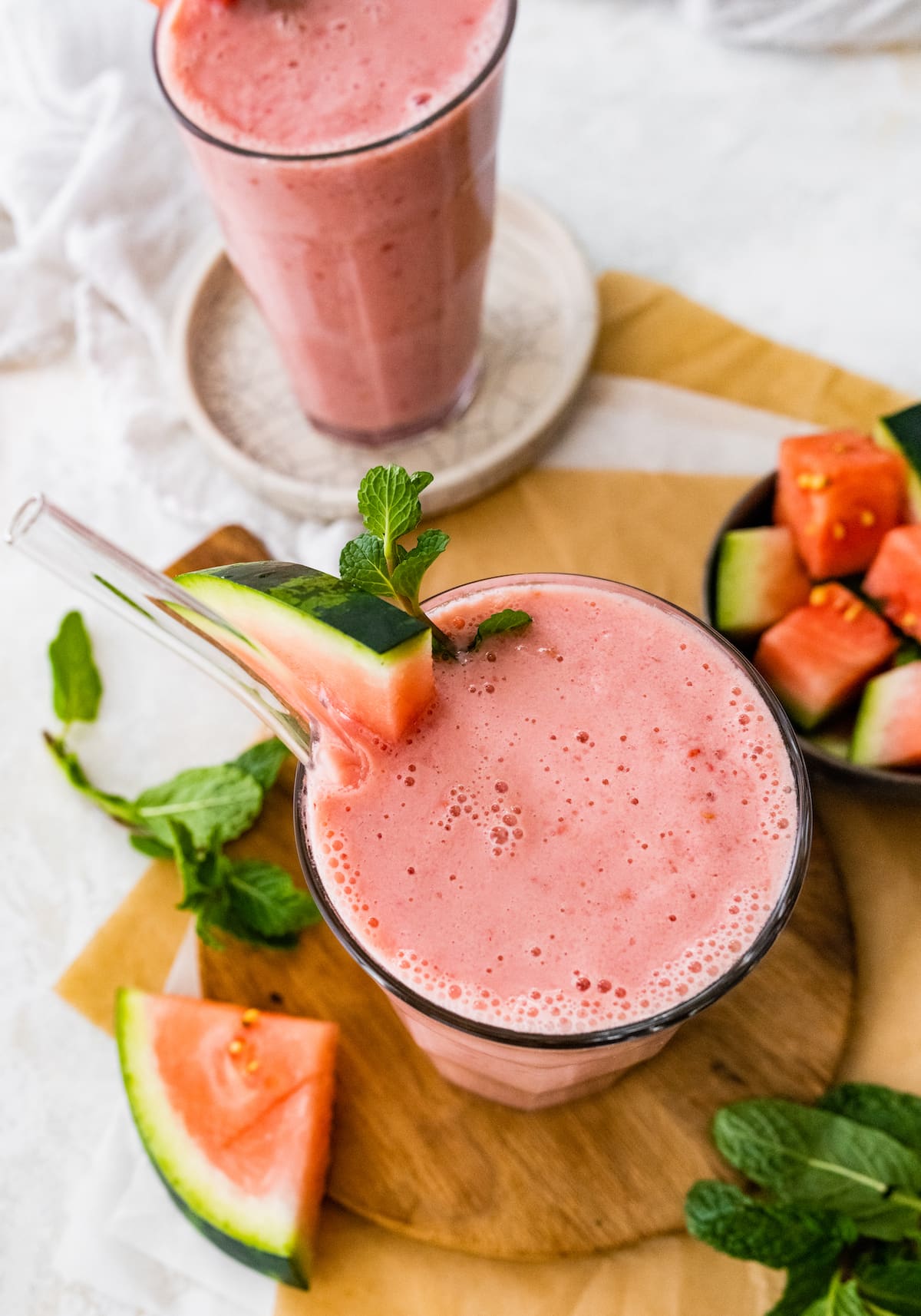 Watermelon smoothie with straw and fresh watermelon slice.