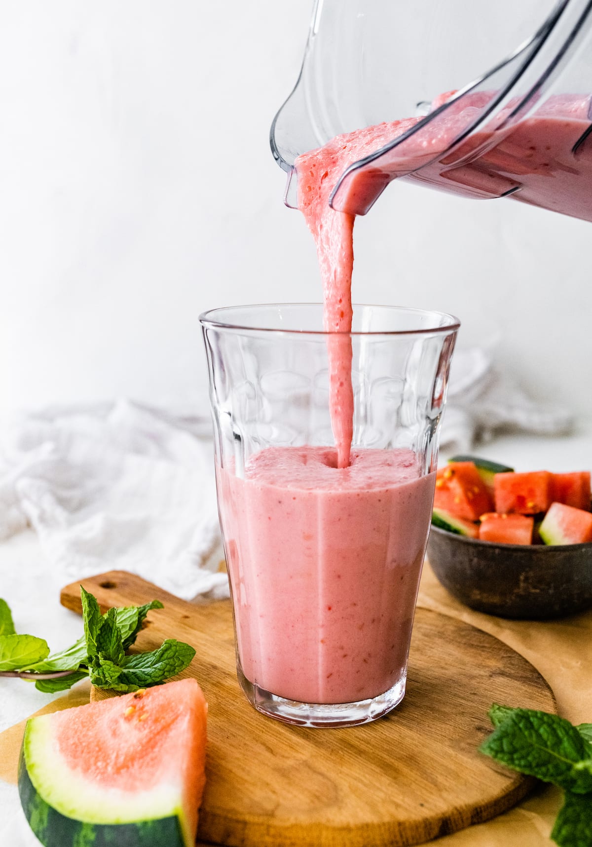 Watermelon smoothie being poured into a glass.