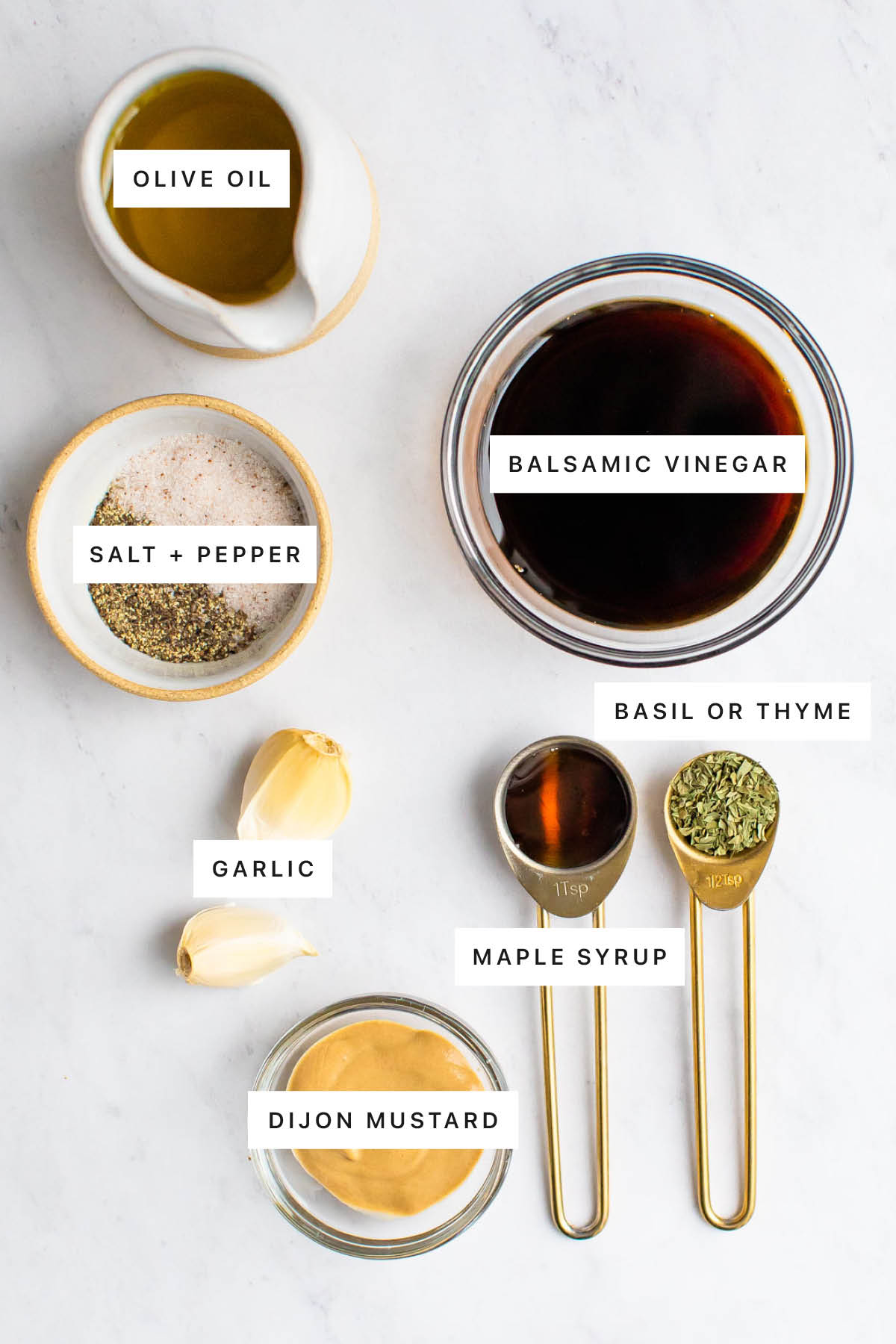 Ingredients measured out to make Balsamic Vinaigrette Dressing: olive oil, balsamic vinegar, salt, pepper, garlic, basil or thyme, maple syrup and dijon mustard.