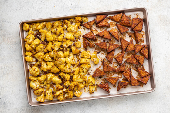 Seasoned tempeh and cauliflower on a baking tray after baking in the oven.