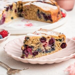 A slice of easy berry cake on a light pink plate.