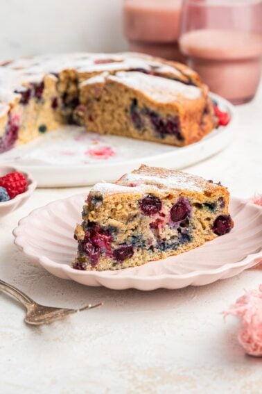 A slice of easy berry cake on a light pink plate.