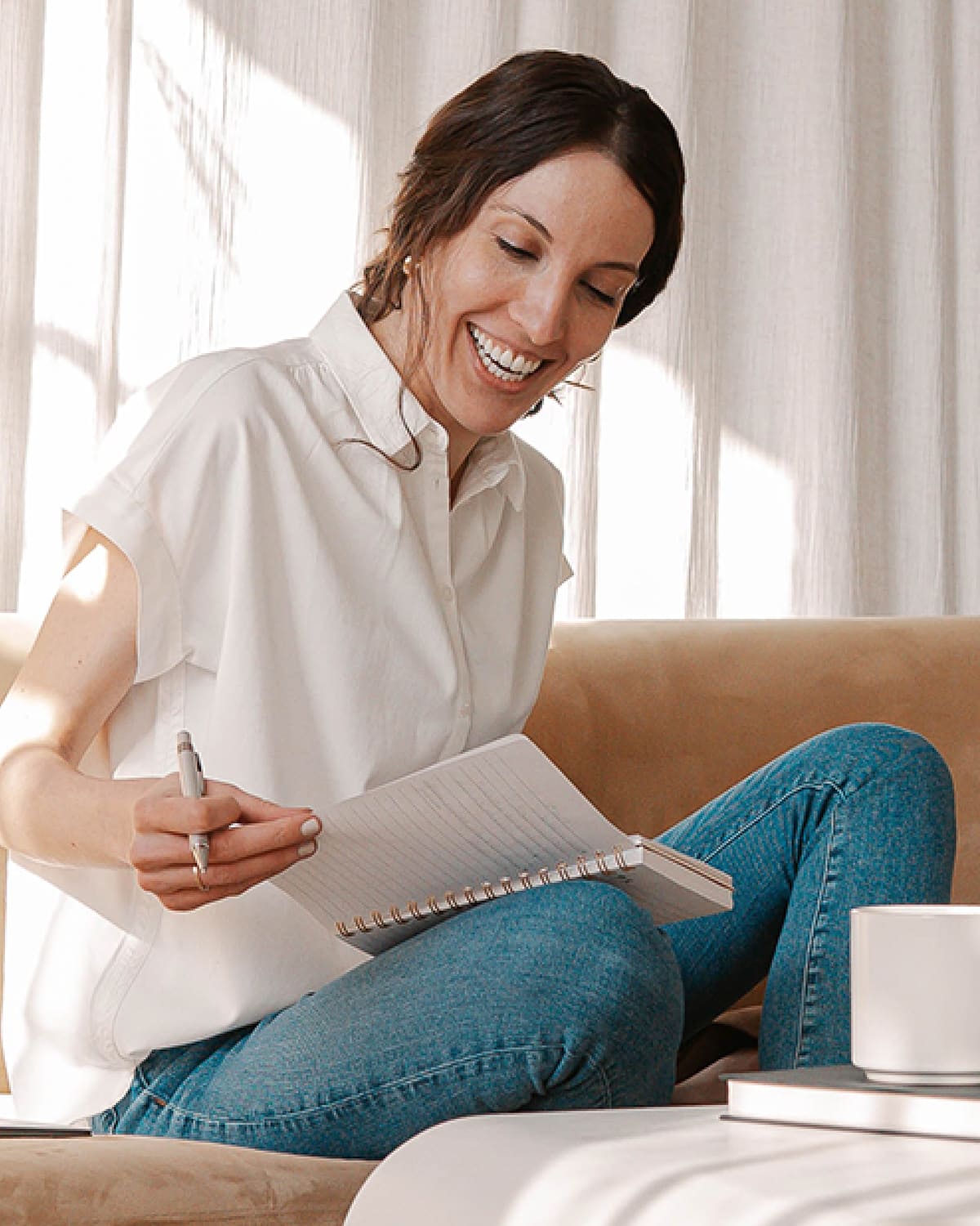 A woman in a white shirt looking at a journal.