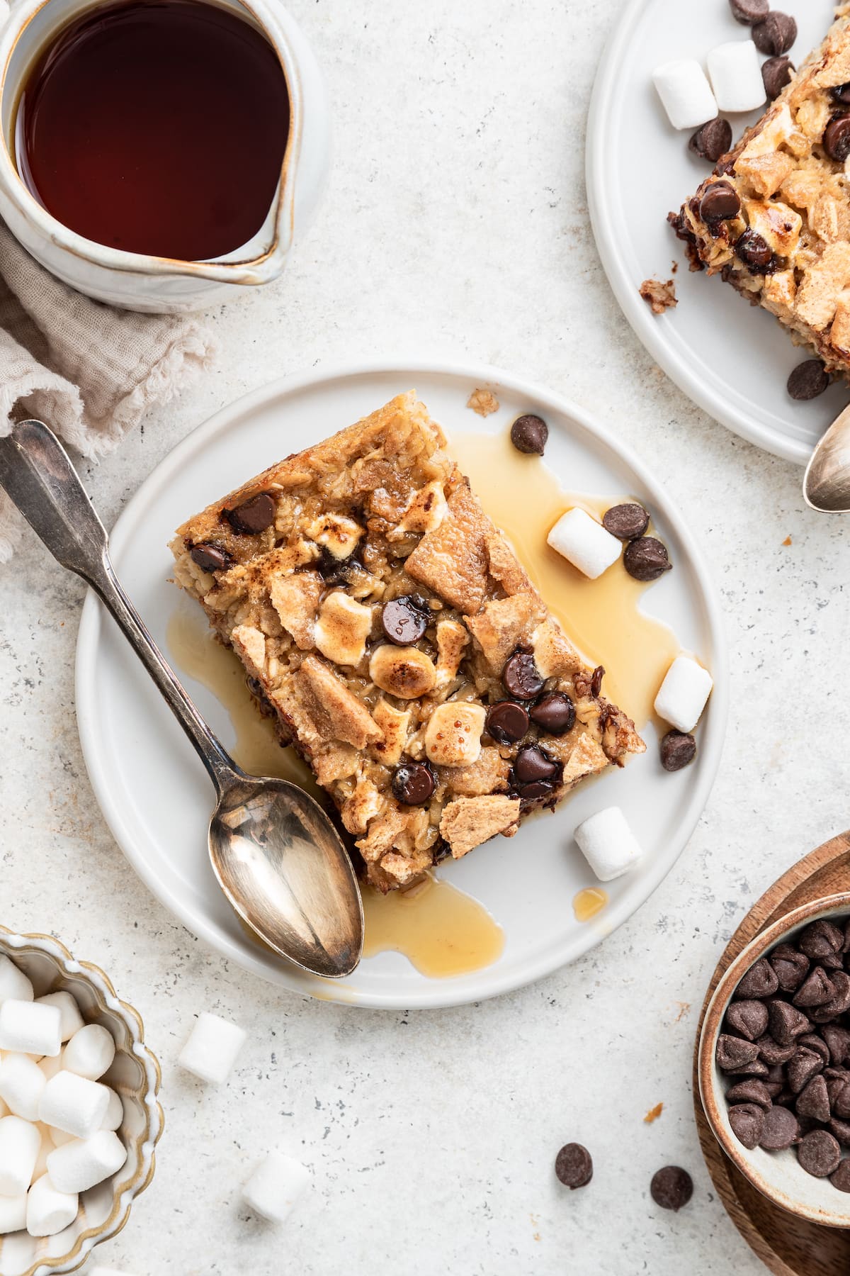 A small white plate with a spoon and a piece of the s'mores baked oatmeal lightly covered in maple syrup.