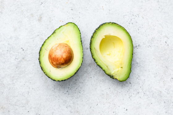 A halved avocado with a pit inside one half.