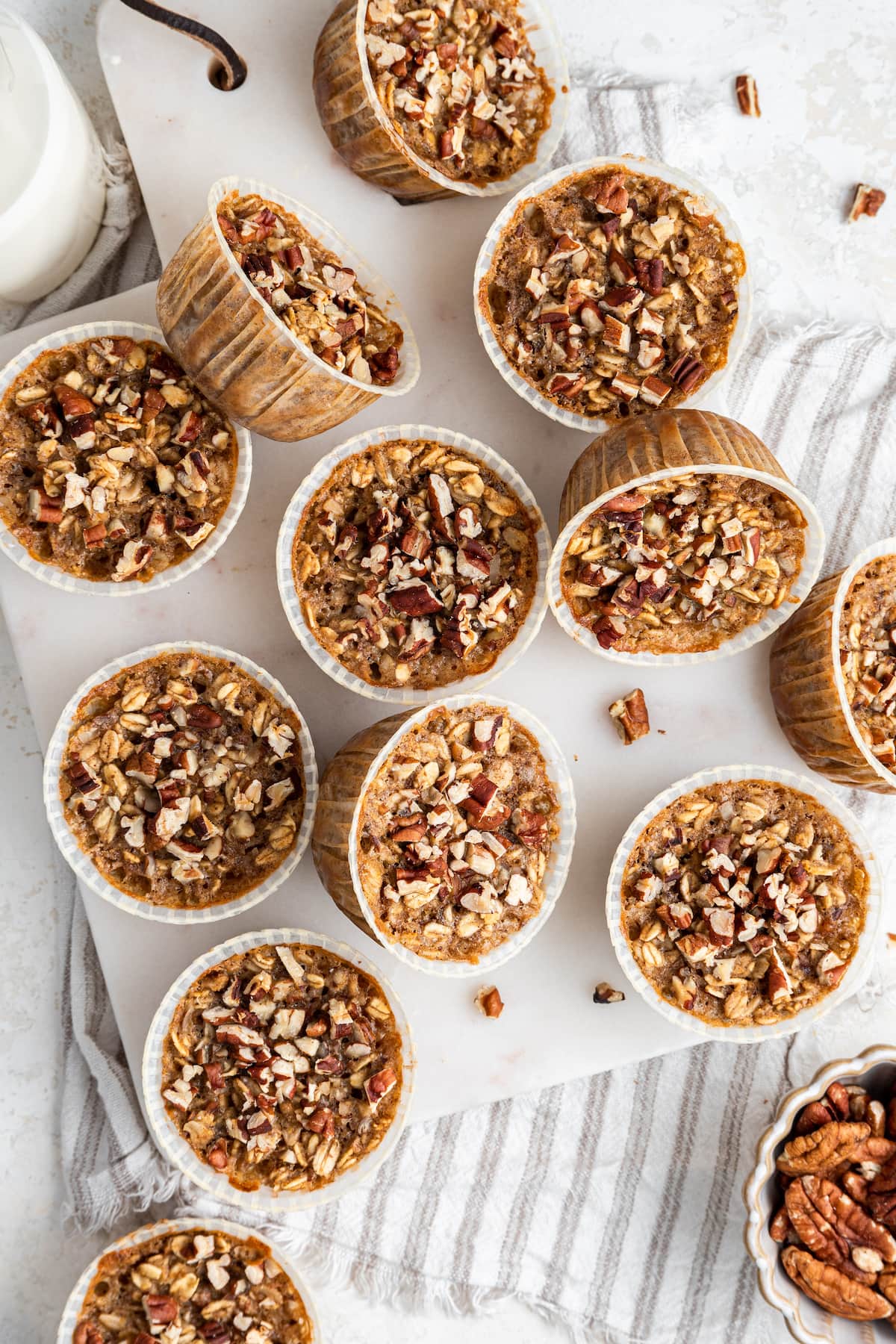 Multiple chai baked oatmeal cups are scattered over a white cutting board.