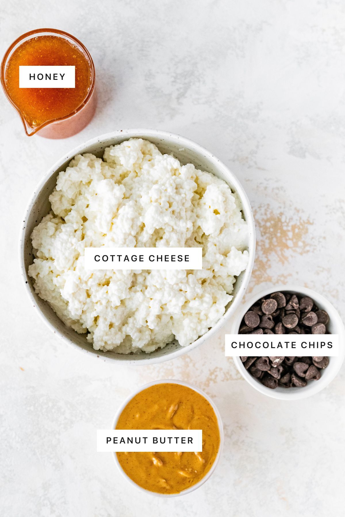 Ingredients for cottage cheese ice cream: honey, cottage cheese, chocolate chips and peanut butter.