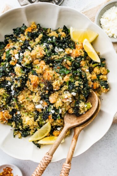 Roasted broccoli quinoa salad in a large white bowl with two wooden serving spoons.