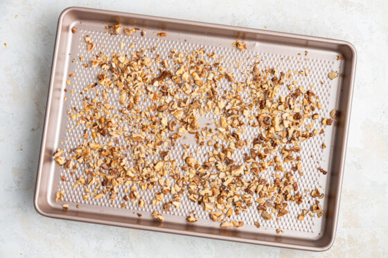 Chopped walnuts on a baking tray.