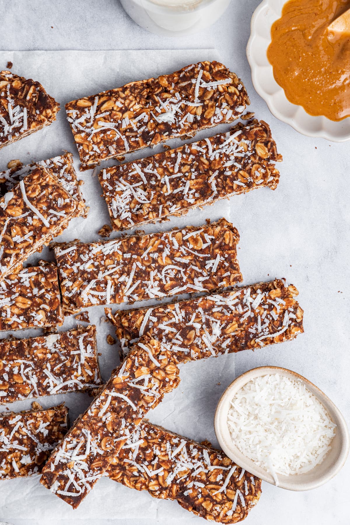 Multiple no-bake chocolate coconut bars scattered on parchment paper.