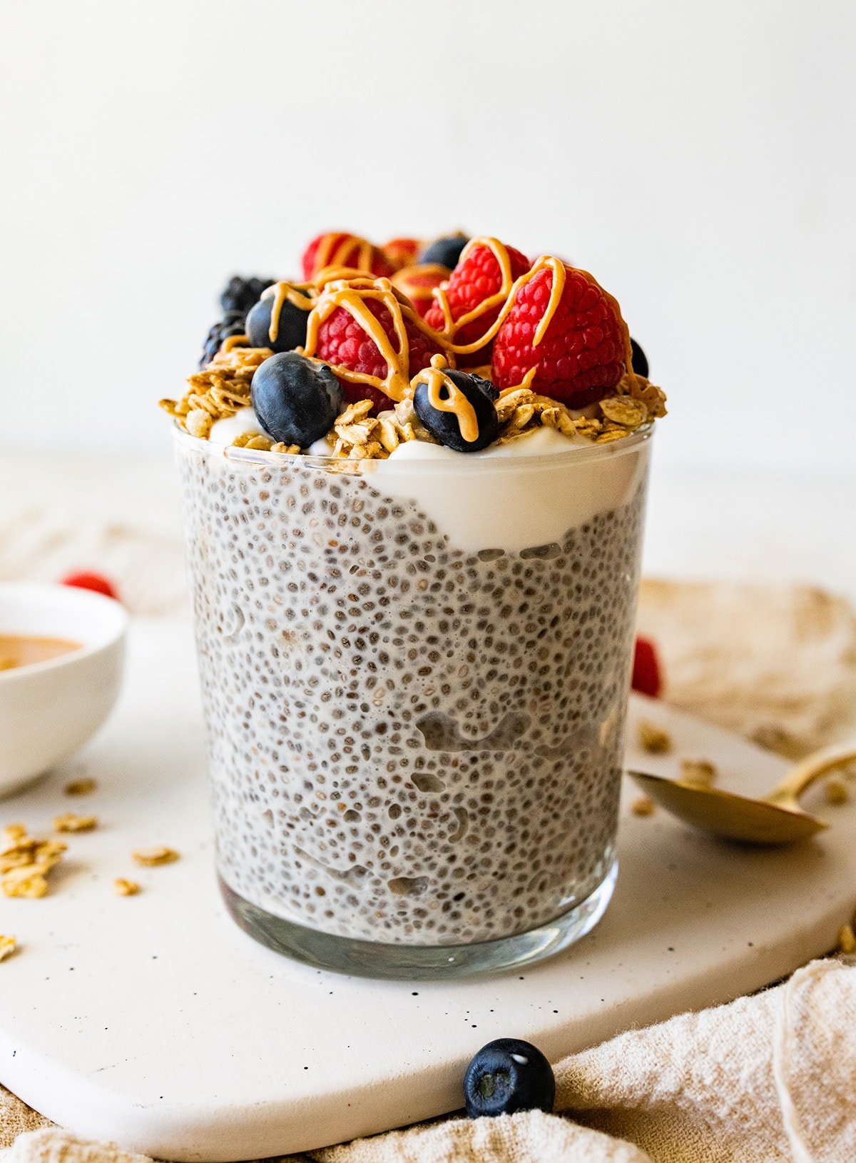 One protein chia pudding jar topped with fresh raspberries, blueberries, blackberries, greek yogurt and a drizzle of nut butter.