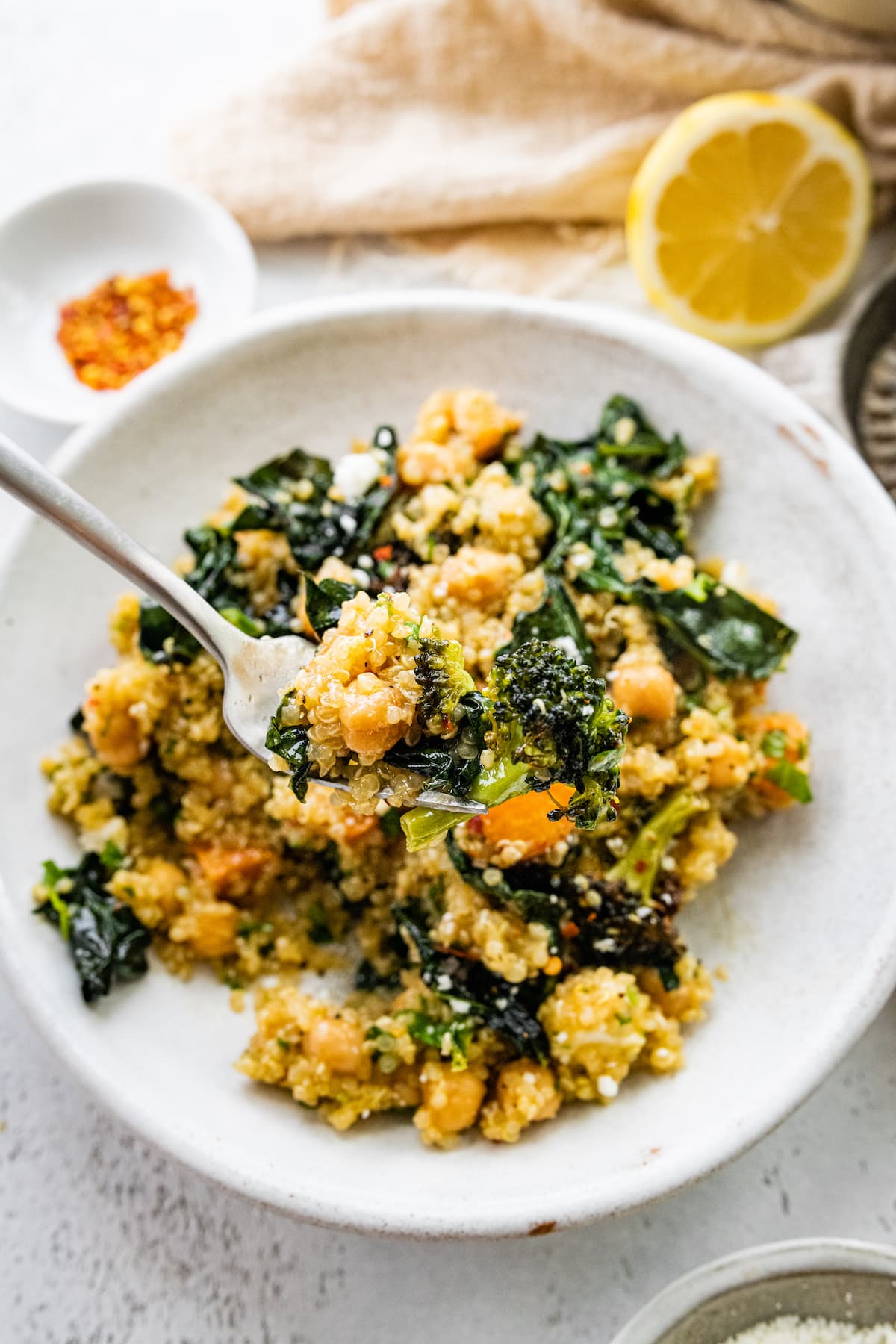 A metal fork with a bite of the roasted broccoli quinoa salad on it.