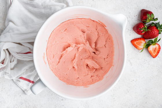A white bowl full of strawberry buttercream frosting.