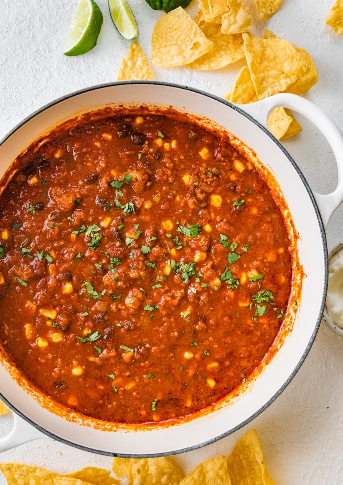 Turkey chili in a large, white dutch oven, topped off with a sprinkle of fresh cilantro.