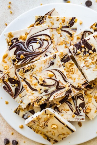 Frozen cottage cheese bark with dark chocolate and granola cut into squares and served on a white plate.