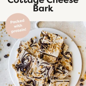 Frozen cottage cheese bark with dark chocolate and granola cut into squares and served on a white plate.