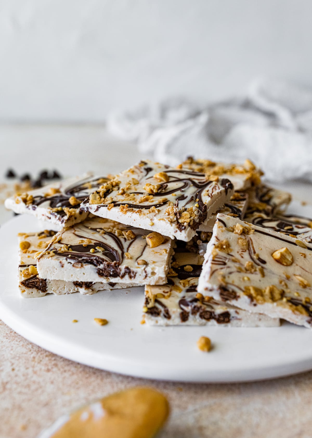 Frozen cottage cheese bark with dark chocolate and granola cut into squares and served on a white plate.