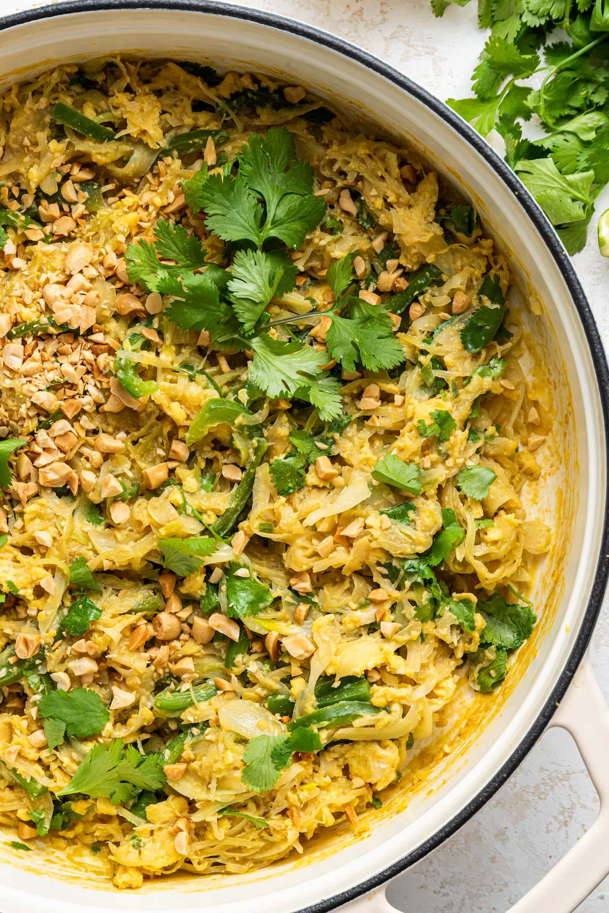 Healthy Pad Thai in a large white pot garnished with fresh cilantro and peanuts.