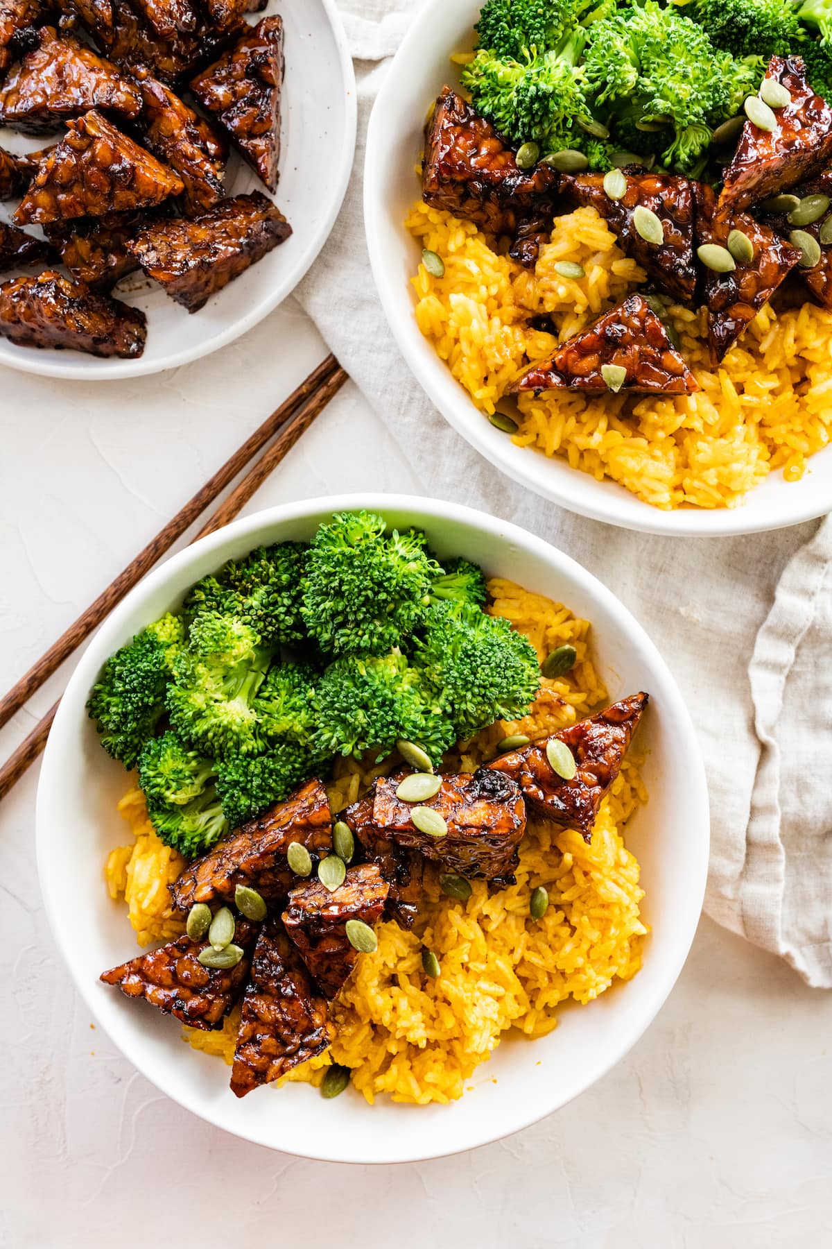 Two bowls with maple balsamic tempeh, broccoli, pumpkin seeds, and pumpkin rice.