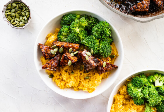 A white bowl with maple balsamic tempeh, broccoli, pumpkin seeds, and pumpkin rice.