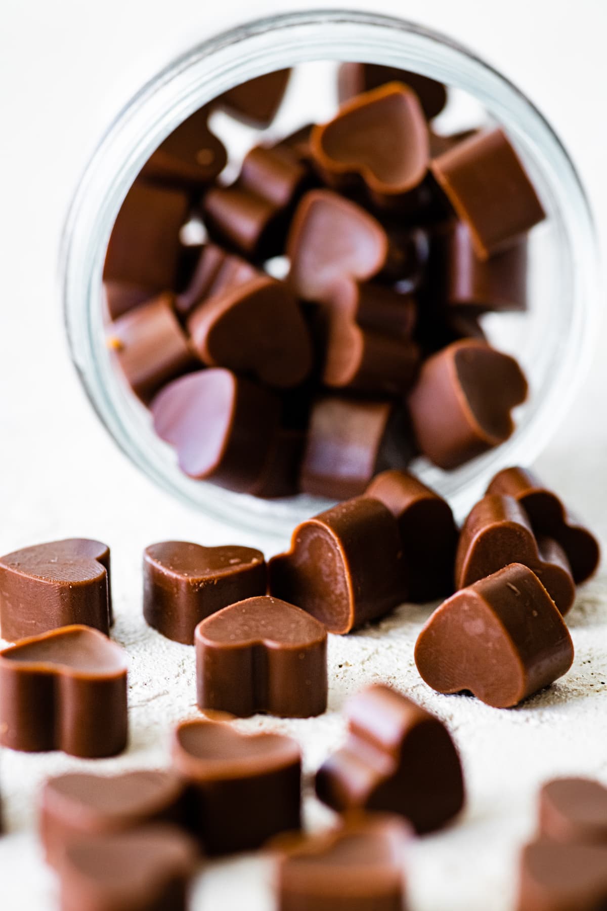 A close up photo of heart-shaped poop chocolates falling out of a glass jar.