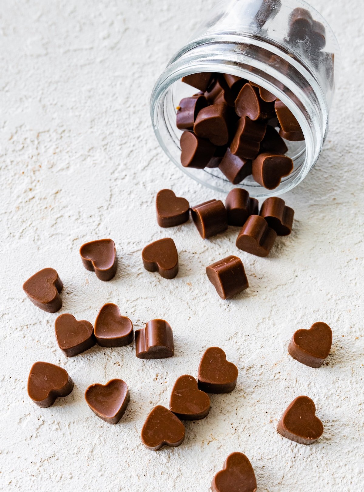 Heart-shaped poop chocolates falling out of a glass jar.