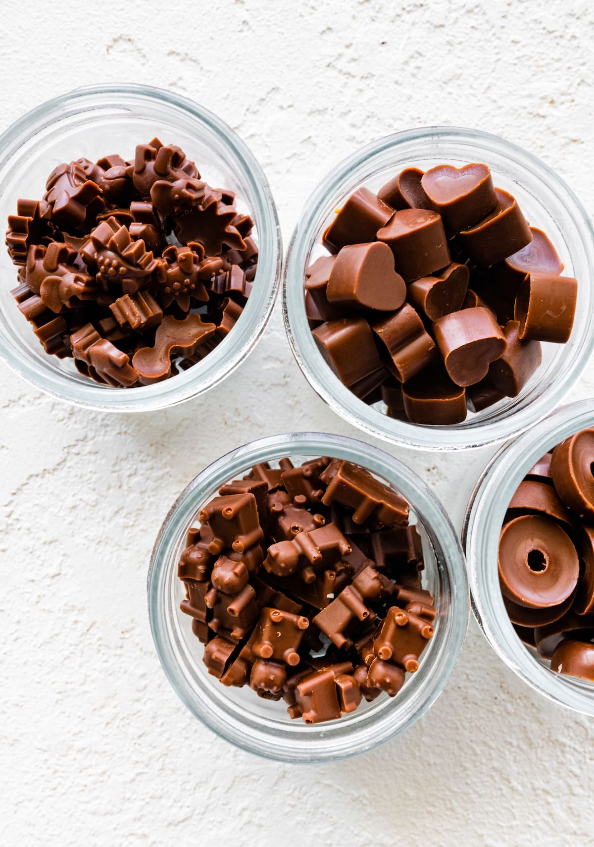 Four glass jars filled with different shaped poop chocolates.