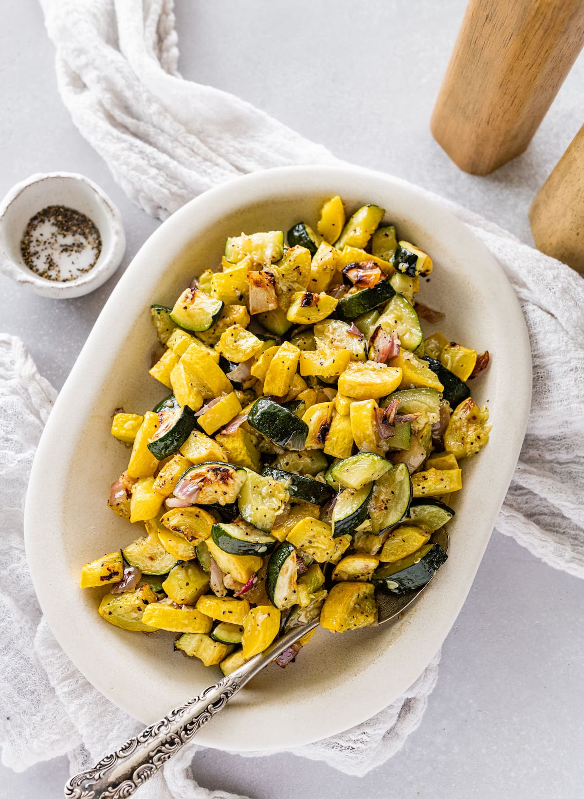 Roasted zucchini and squash in a white serving bowl.