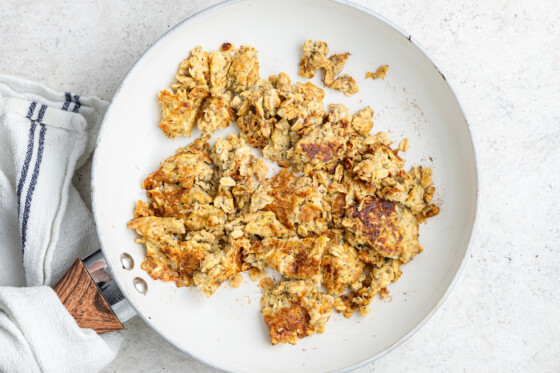 Cooked scrambled oats in a white skillet.