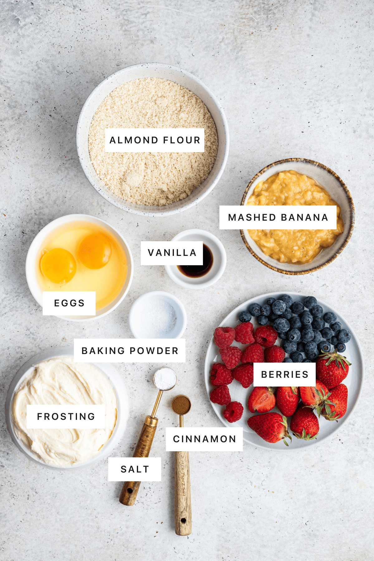 Ingredients for the healthy smash cake: almond flour, mashed banana, eggs, vanilla, baking powder, salt, cinnamon, berries and frosting.