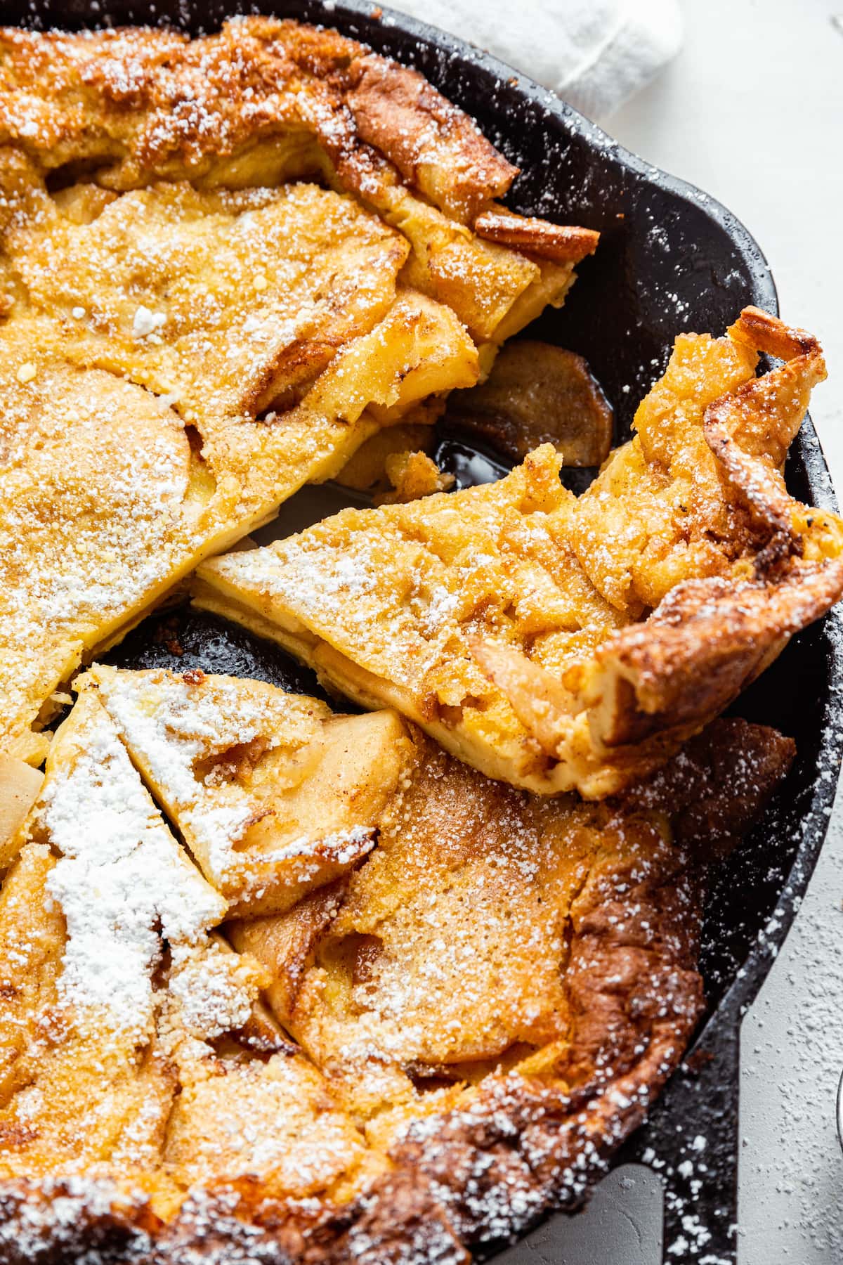 An apple dutch baby sliced in a cast iron pan.