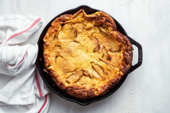 A cooked apple dutch baby in a cast iron pan.