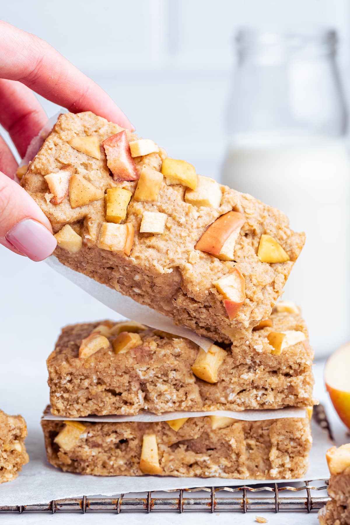 A woman's hand holding an apple oatmeal bar over two other bars.