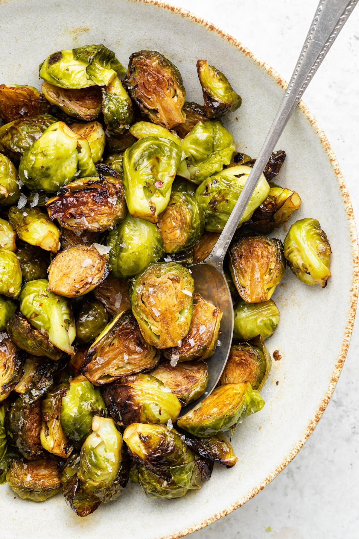 Balsamic Brussels Sprouts on a white plate with a metal spoon.