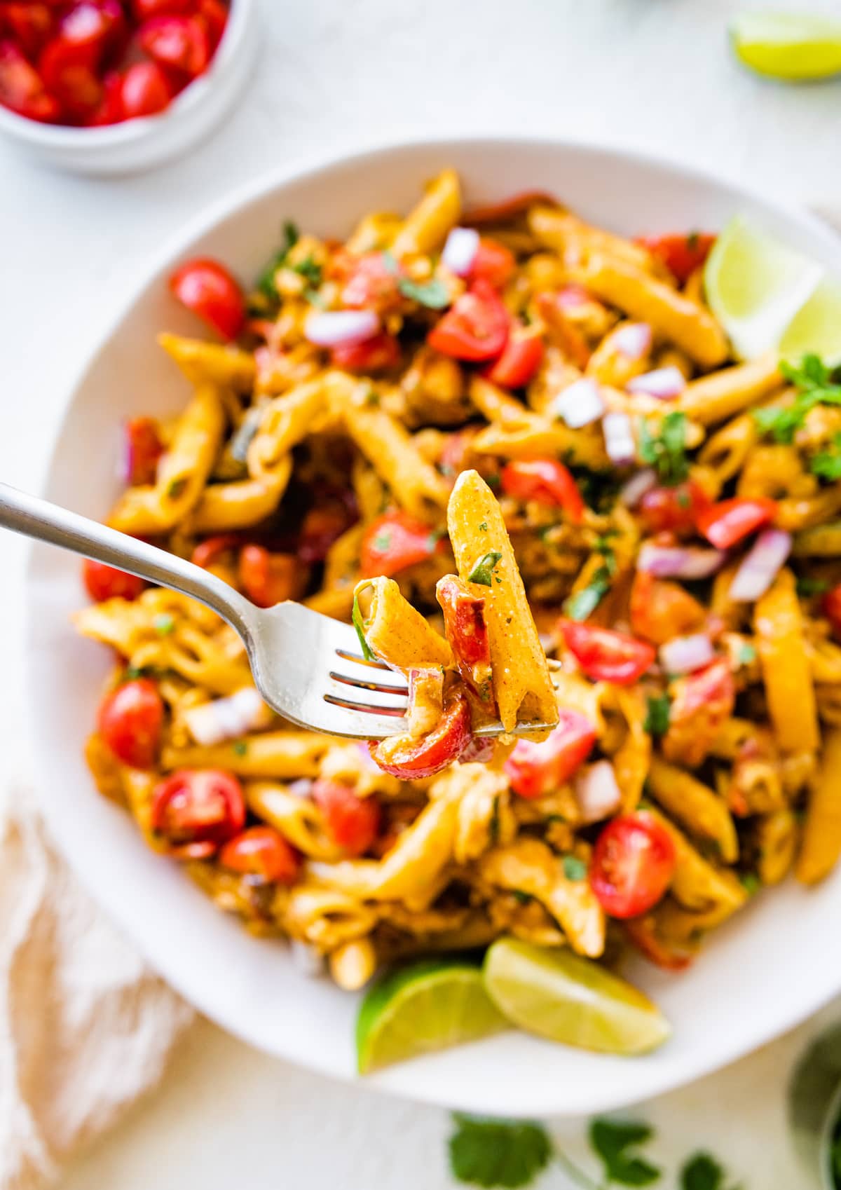 Chicken fajita pasta salad on a white plate and a fork taking a bite-size portion.