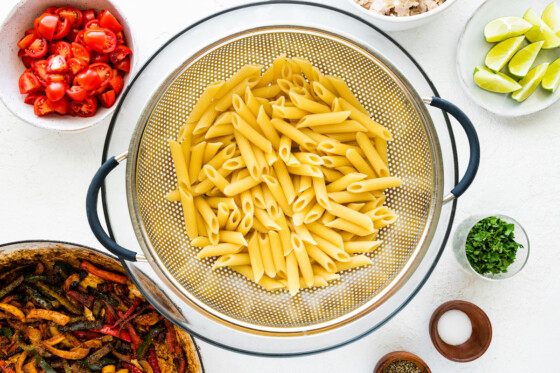 Penne pasta in a metal colander.