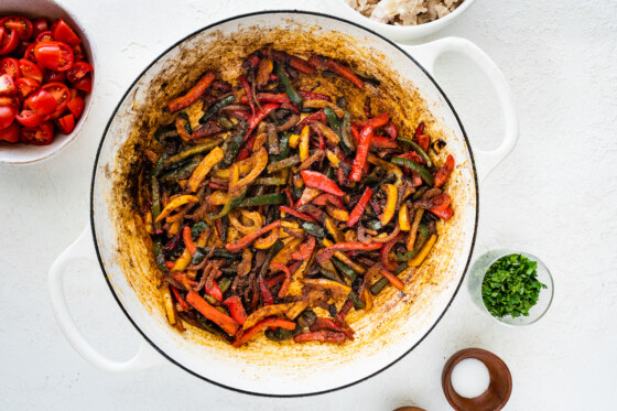 Cooked and seasoned bell peppers and onions in a large white pot.