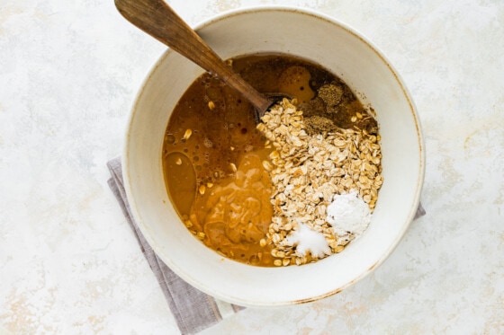 All the ingredients for the coffee baked oatmeal in a large mixing bowl with a wooden spoon.