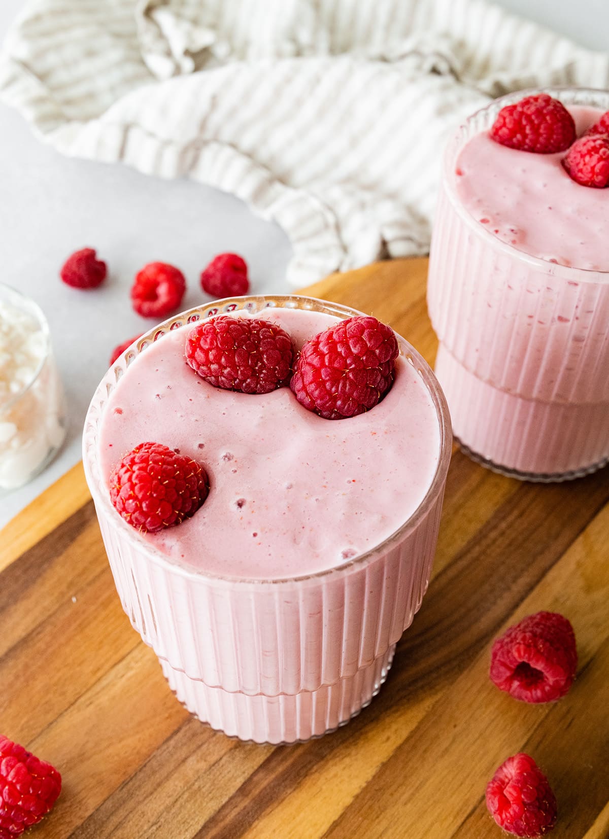 Two cottage cheese smoothies topped with fresh raspberries.