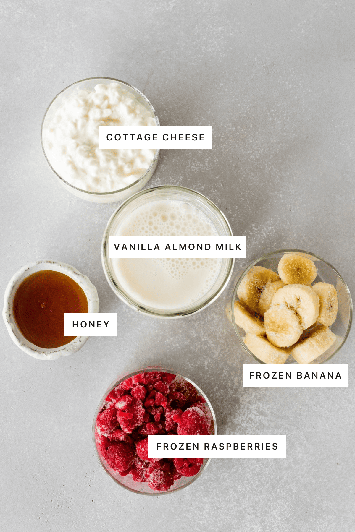 Ingredients for the cottage cheese smoothie: cottage cheese, almond milk, frozen bananas, frozen raspberries and honey.