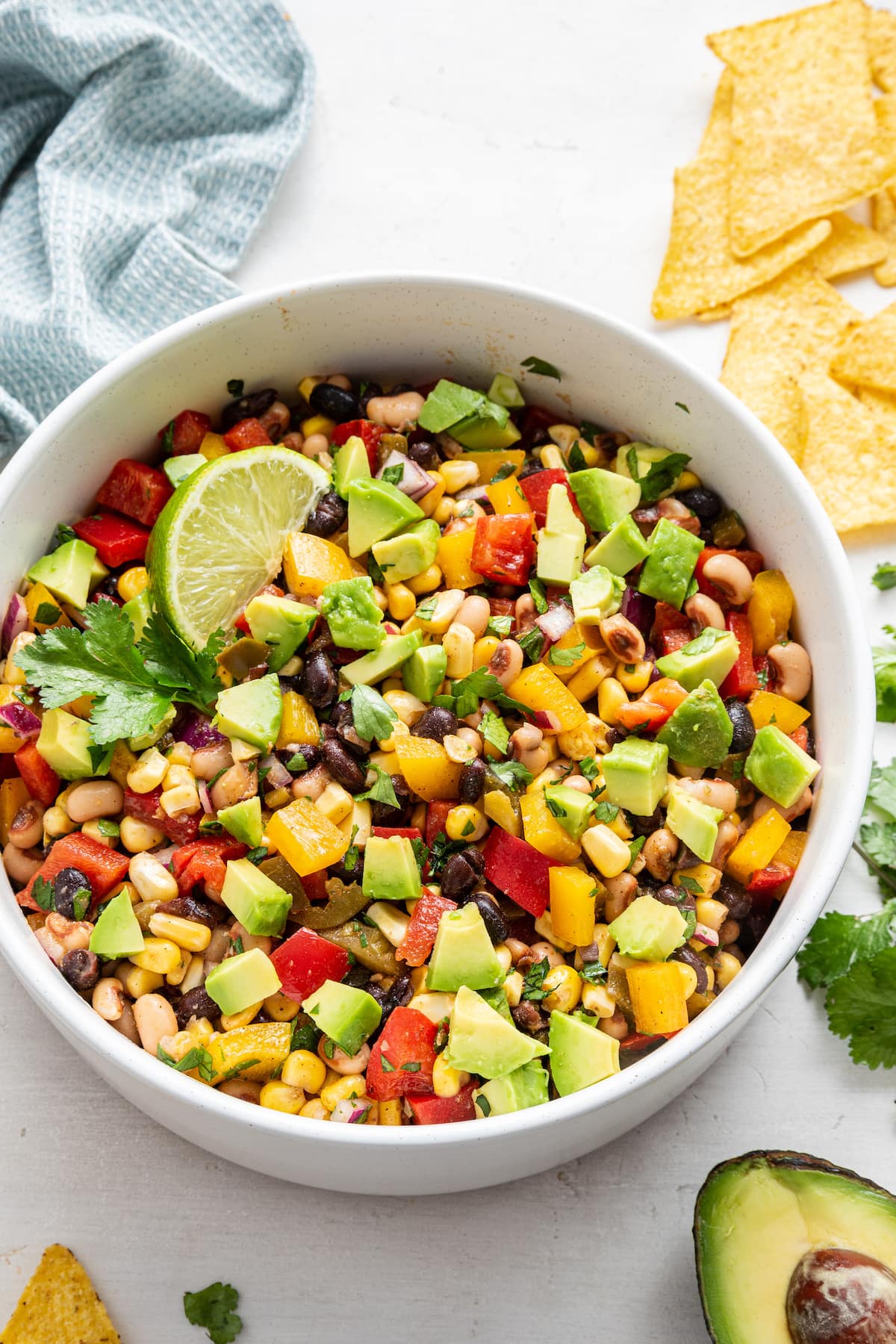 Cowboy caviar in a white bowl with diced avocado and a lime wedge.