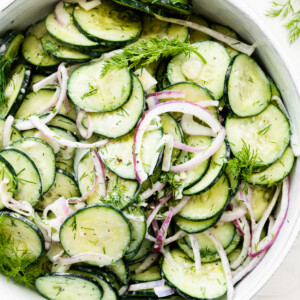 Creamy cucumber salad in a large white bowl.