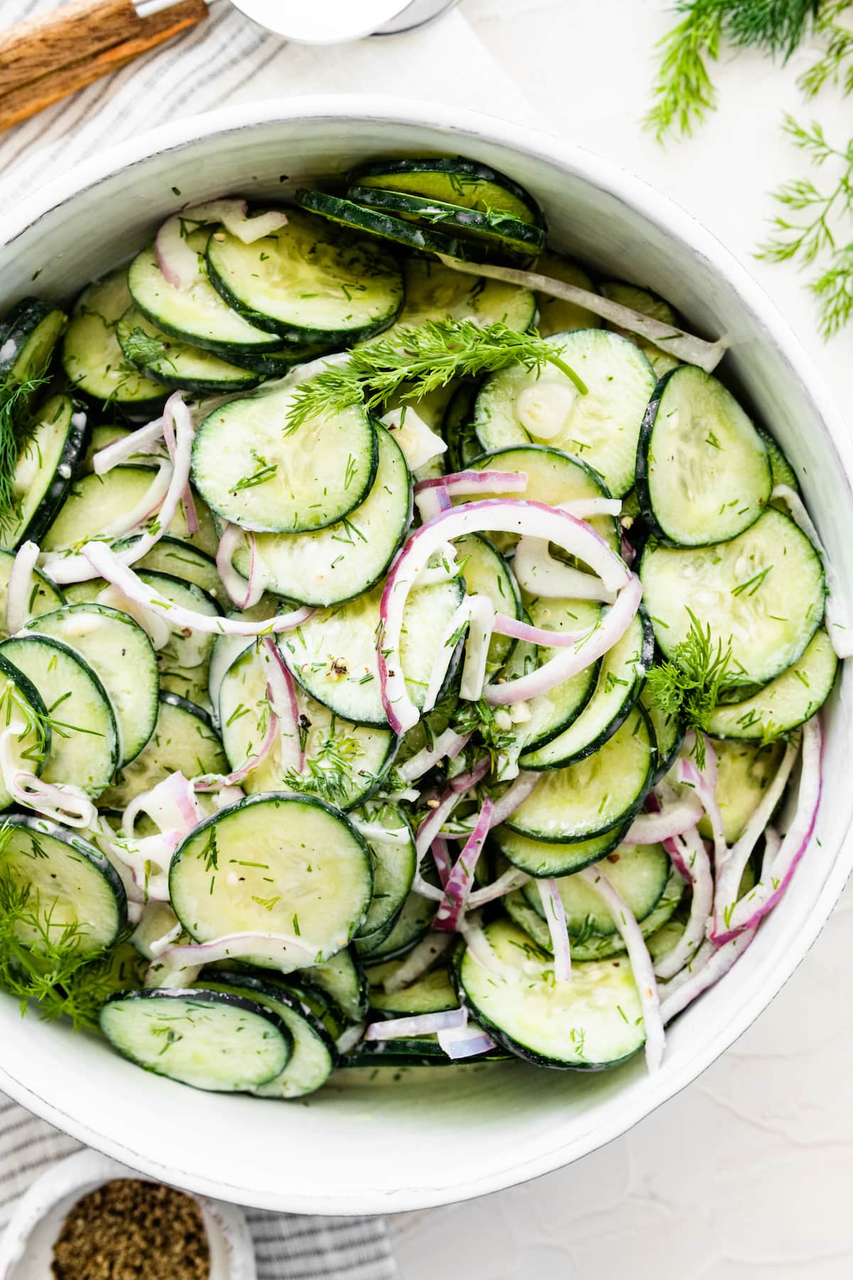Creamy cucumber salad in a large white bowl.