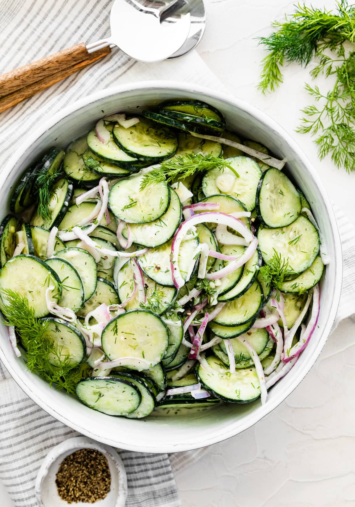 Creamy cucumber salad in a large white bowl.