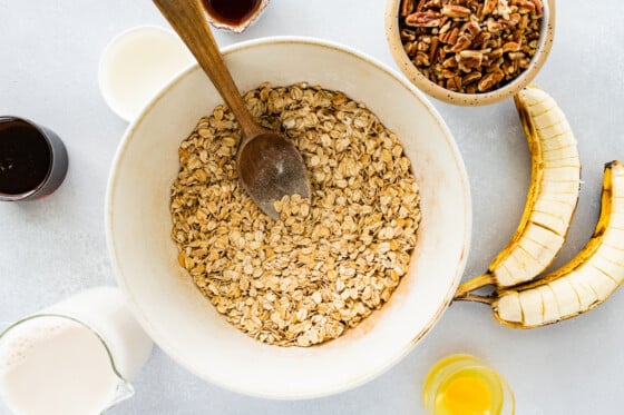 Dry ingredients for baked oatmeal mixed together in a white mixing bowl with a wooden spoon.